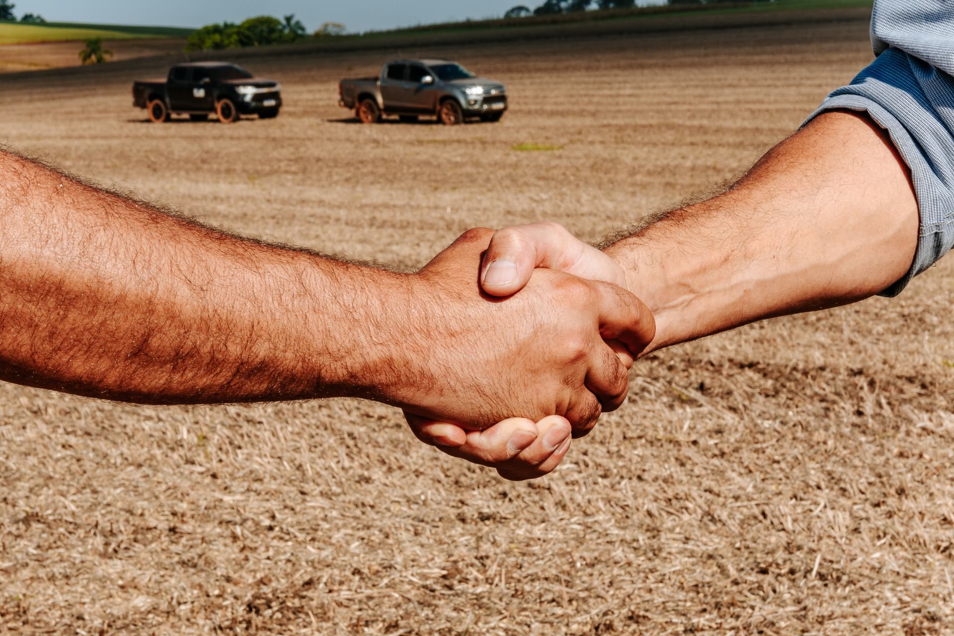 Aperto de mão no campo entre produtor e consultor